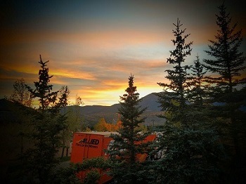 An Atlas Allied moving truck driving through a forest, illuminated by the sunset, near the Orange County coastline