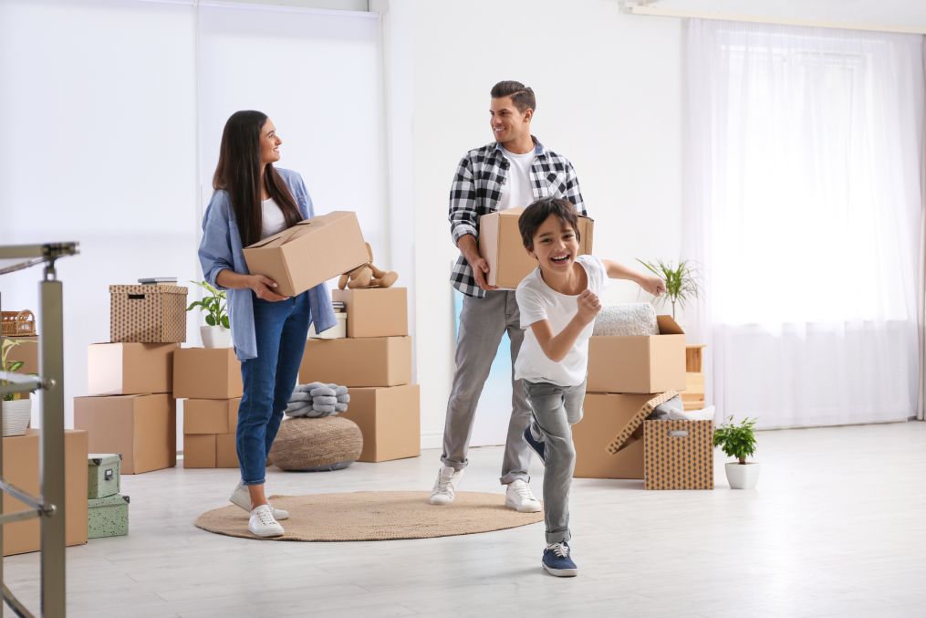 Happy family in room with cardboard boxes on moving day