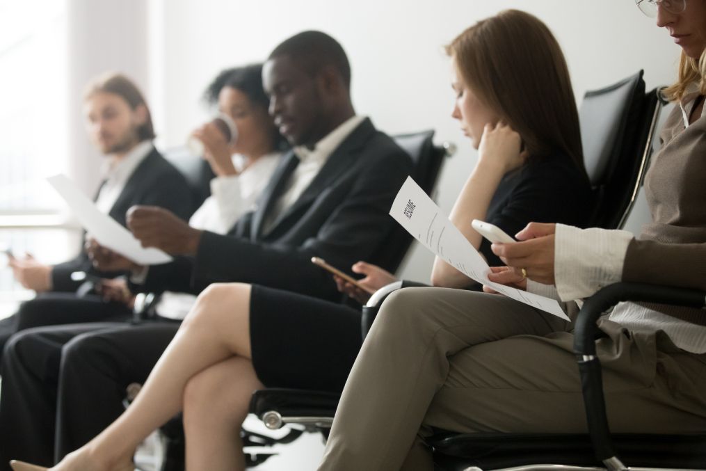 Multi-ethnic applicants sitting in queue preparing for interview.