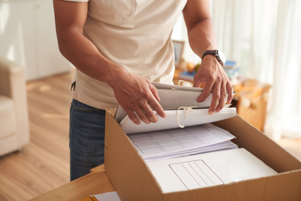 Closeup portrait of young man sorting financial documents in paper folders at home