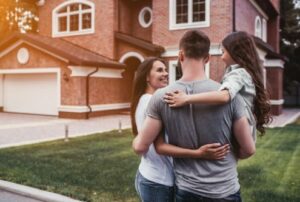 Back view of happy family is standing near their modern house and hugging