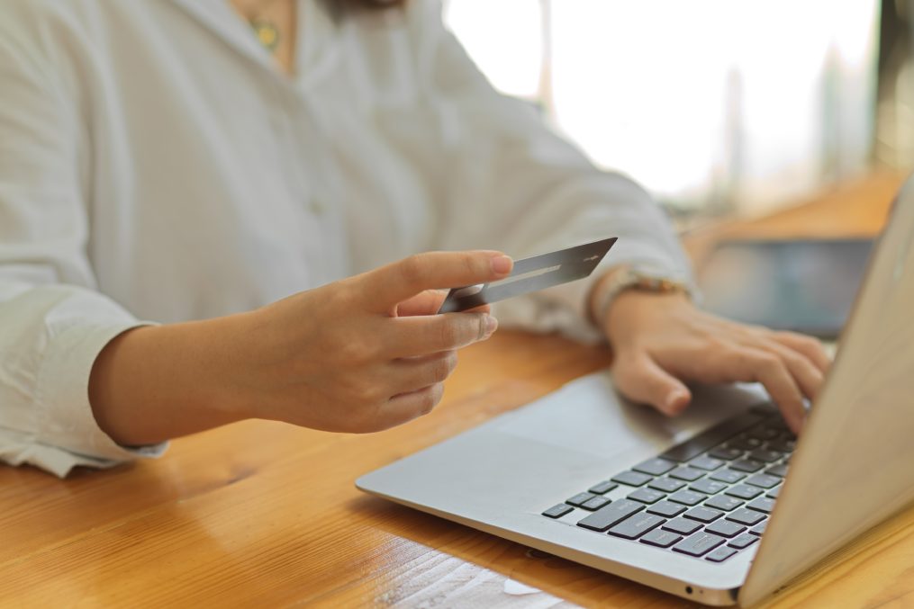 Close up view of female hand holding credit card while online paying on laptop