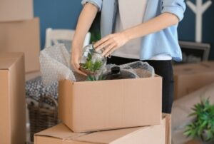 Woman packing carton box indoors. Moving house concept