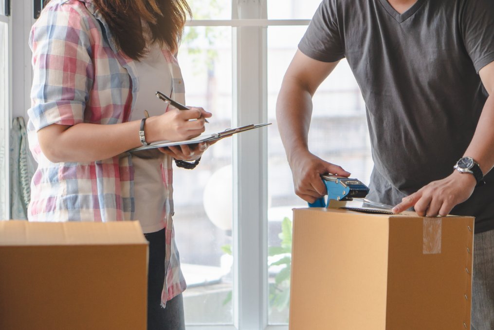 woman checking stuff in cardboard box before sent to transportation company and moving to new location apartment.