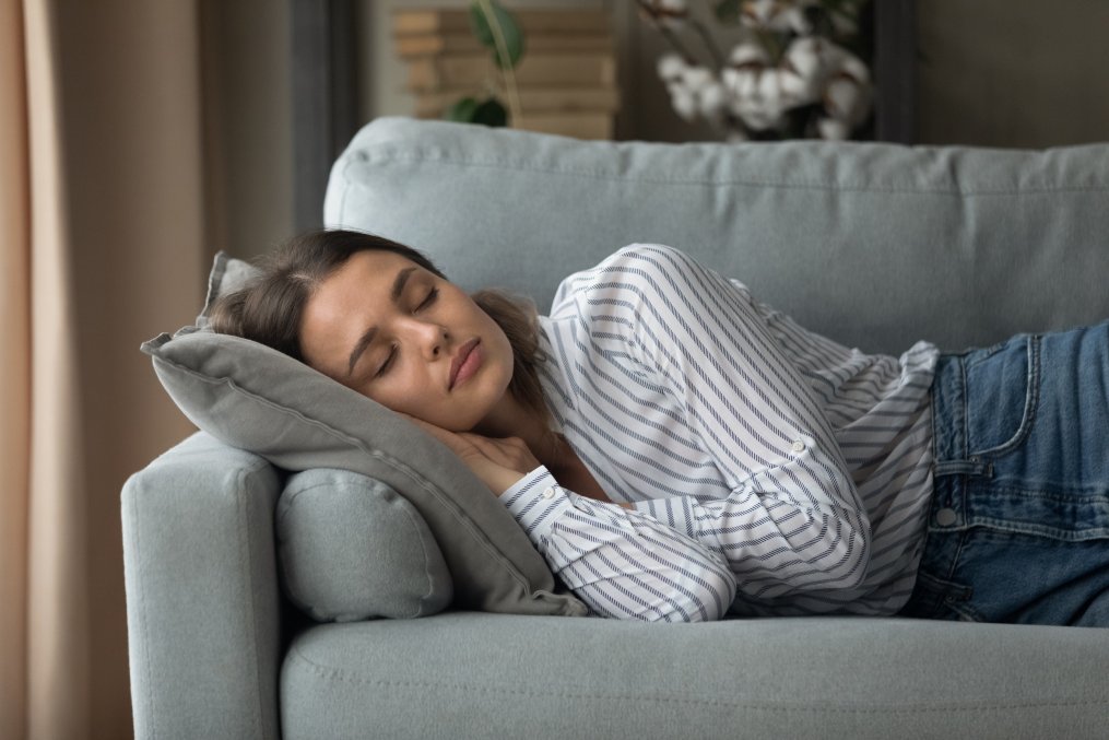 Calm millennial Caucasian woman lying relaxing on couch in living room sleeping taking nap. Tired exhausted young female rest on sofa at home daydream relieving negative emotions. Stress free concept.