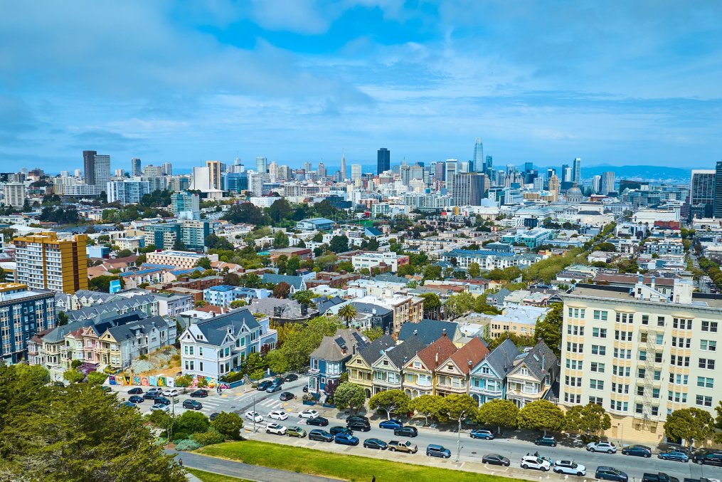 Aerial San Francisco The Painted Ladies with wide view of city and skyscrapers under pretty sky