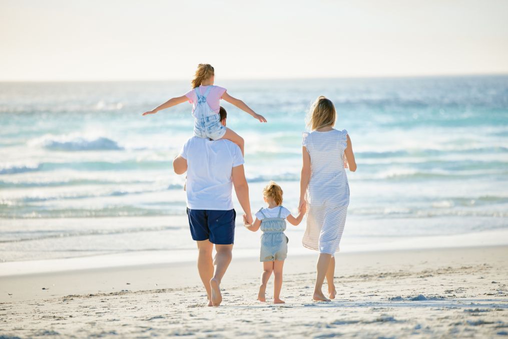 Happy family walking the beach. Rear view of young parents with children having fun on vacation. Little boy and girl enjoying summer with mother and father