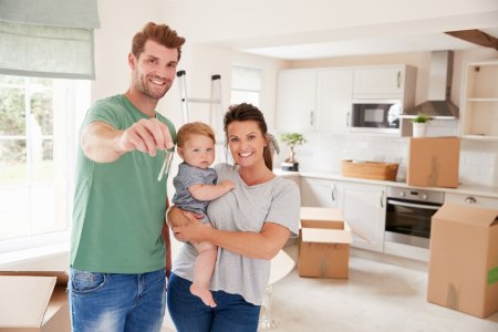 Portrait Of Family With Baby Holding Keys On Moving In Day