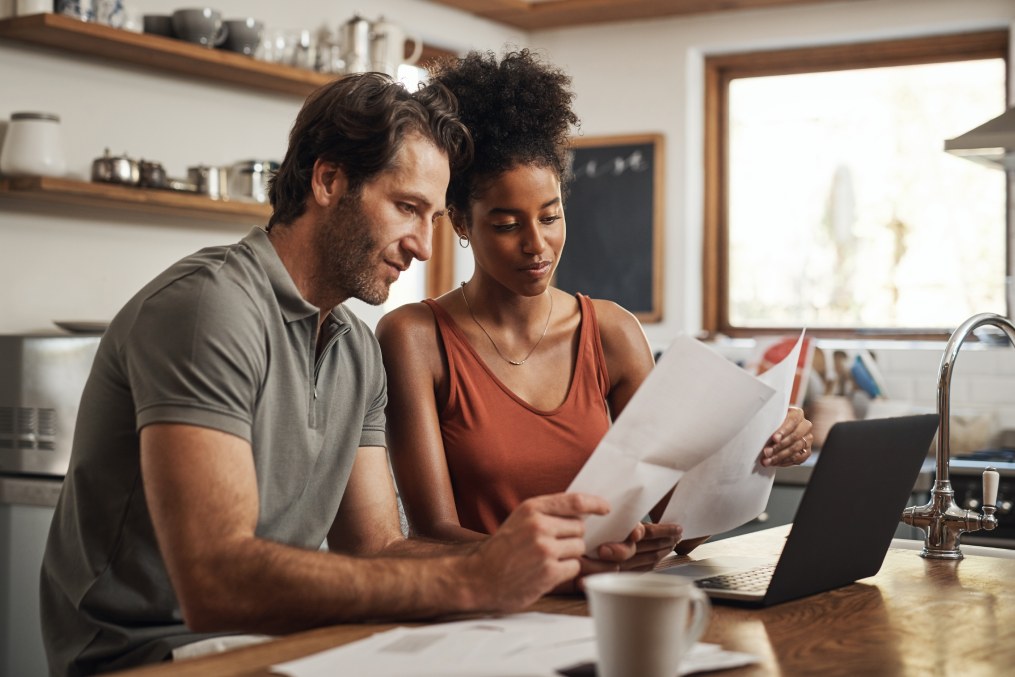 Our debt is almost paid off. Cropped shot of a couple using their laptop and going through paperwork at home.