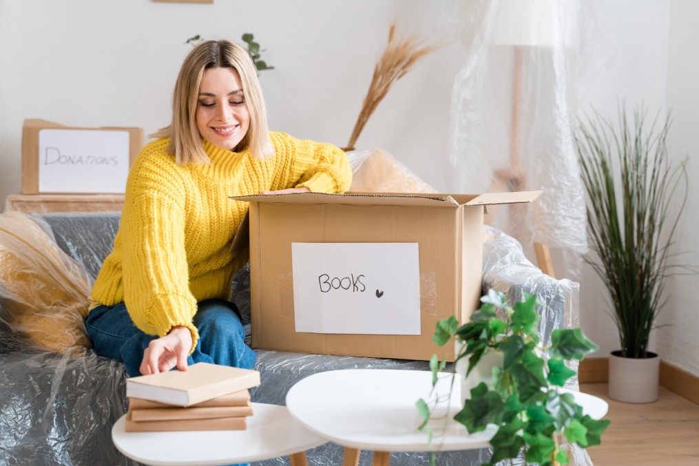 happy woman packing books before moving to a new house