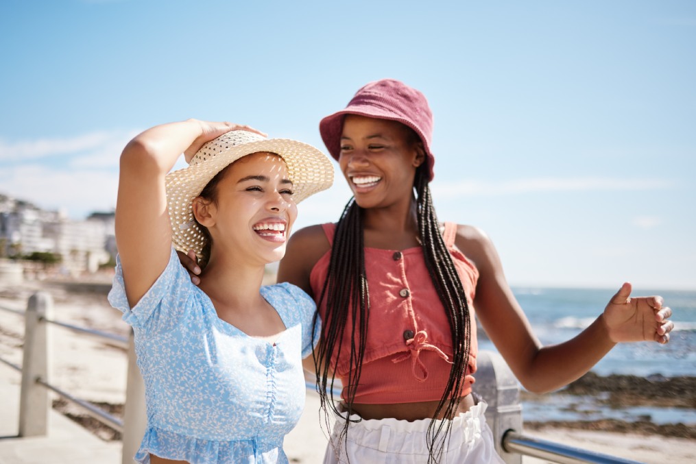 Happy women, friends and summer relax at promenade sea, beach and ocean for fresh air, freedom and fun in Miami Florida. Smile, travel and vacation young people excited for sunshine holiday together
