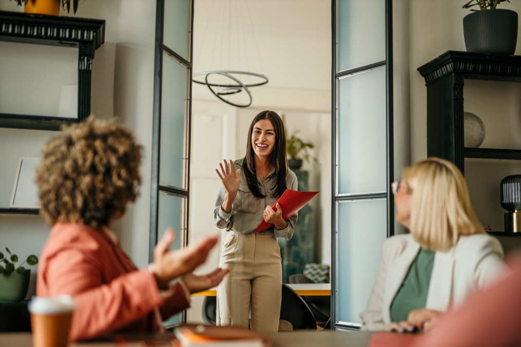 Young female candidate walking into a office, holding a CV, ready to have a job interview with a HR team