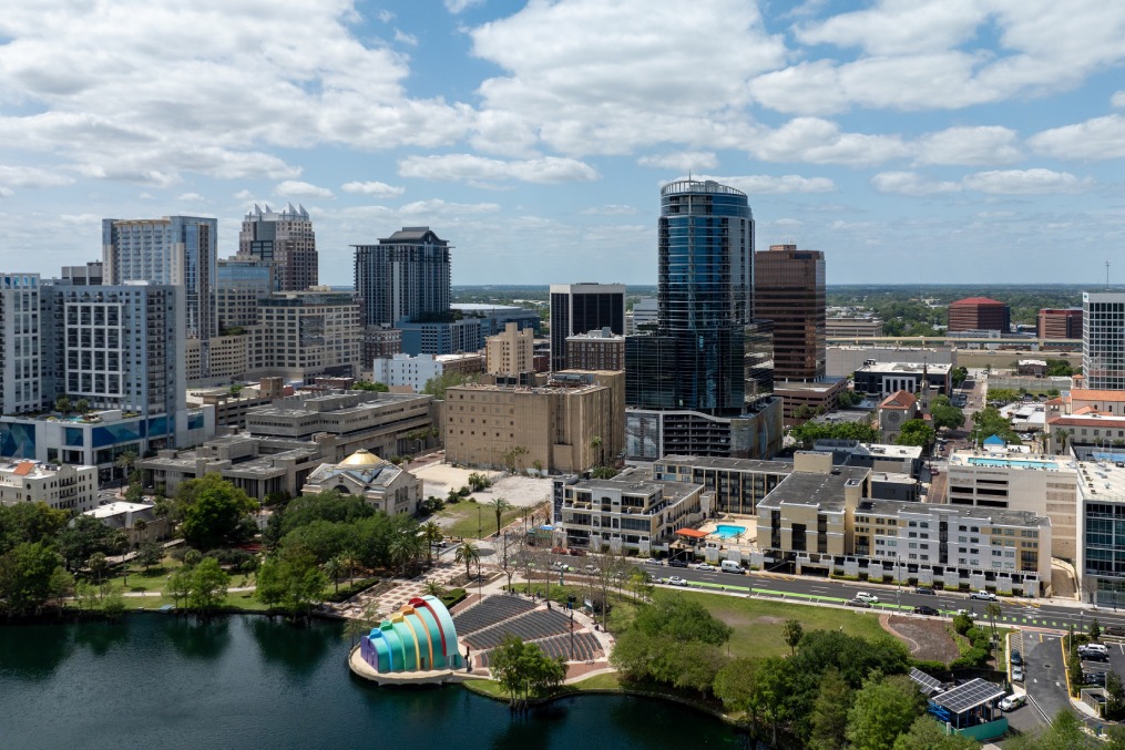 Orlando, Florida, USA - March 27th 2024: A vibrant view of downtown Orlando showcasing a mix of architectural styles among its array of commercial and residential buildings under a partly cloudy sky.