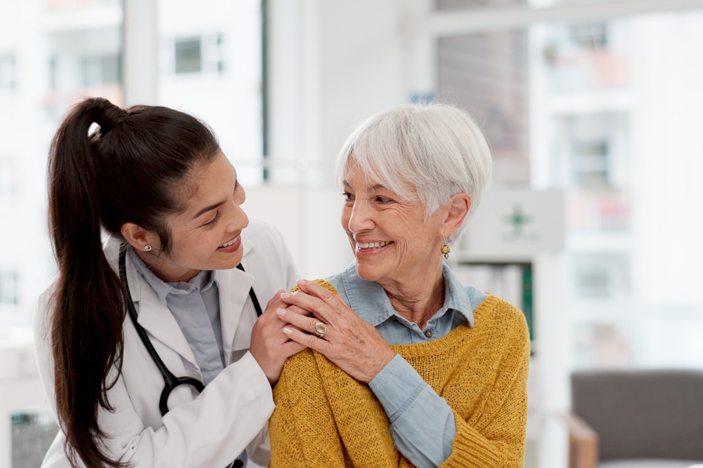 Happy, hug and face of a doctor with a woman for medical trust, healthcare and help. Laughing, care and portrait of a young nurse with a senior patient and love during a consultation at a clinic
