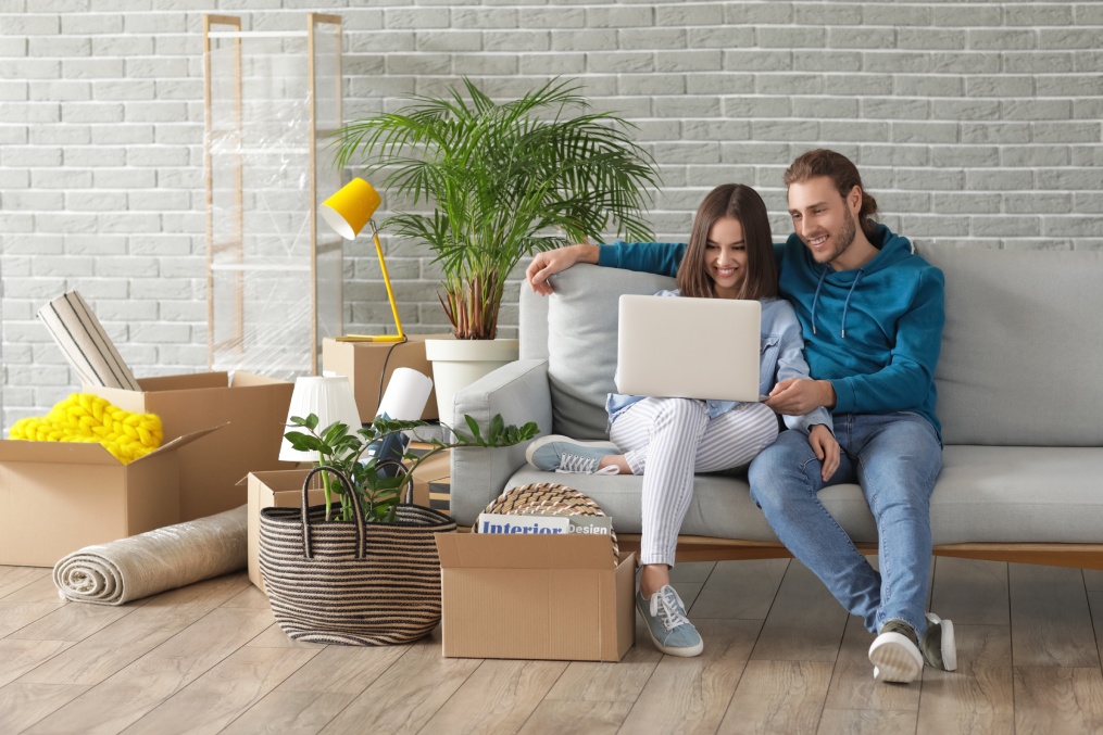 Young couple using laptop in their new house on moving day