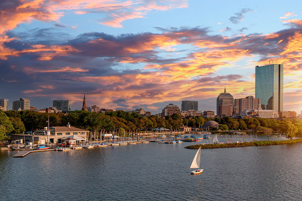 A vibrant city skyline with a sailboat gliding on the water, symbolizing adventure from San Diego to Boston.