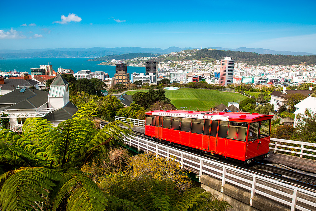 A vibrant red trolley car on tracks, set against a city backdrop, illustrating urban life in a relocation context.