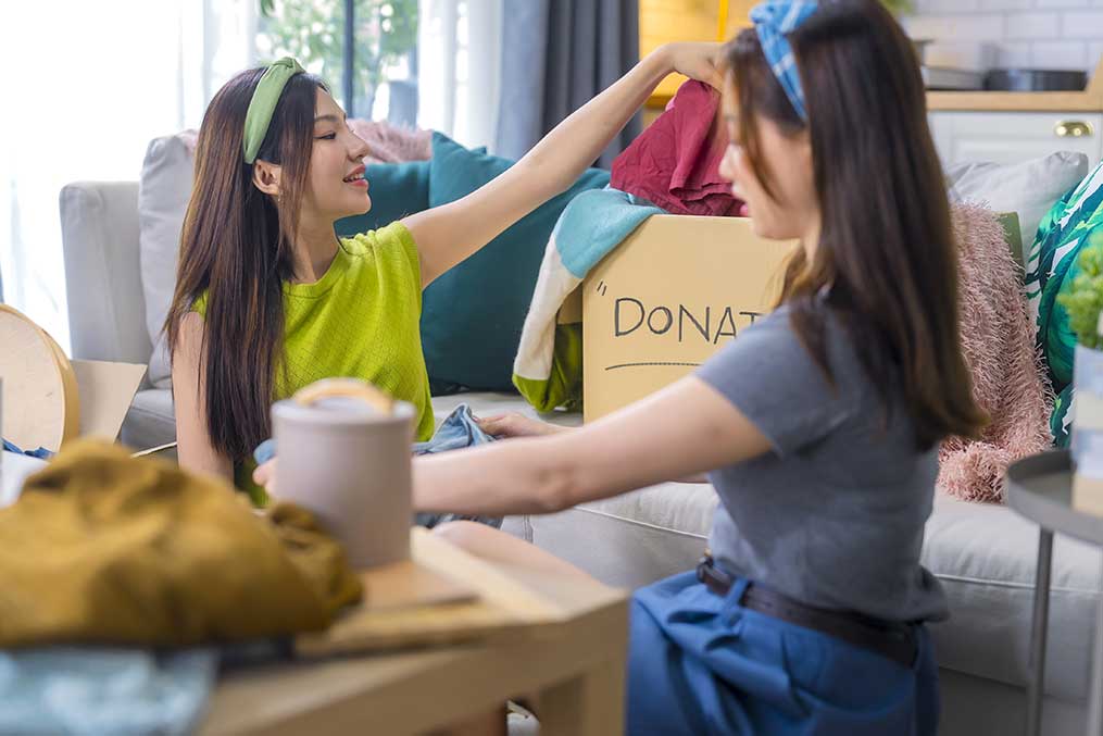 Two women on a couch joyfully hold a box, representing a feature from the Del Mar luxury coastal community guide.