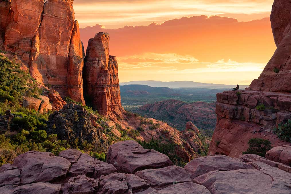 The sun sets over the red rocks of Sedona, Arizona, casting warm hues across the desert landscape.