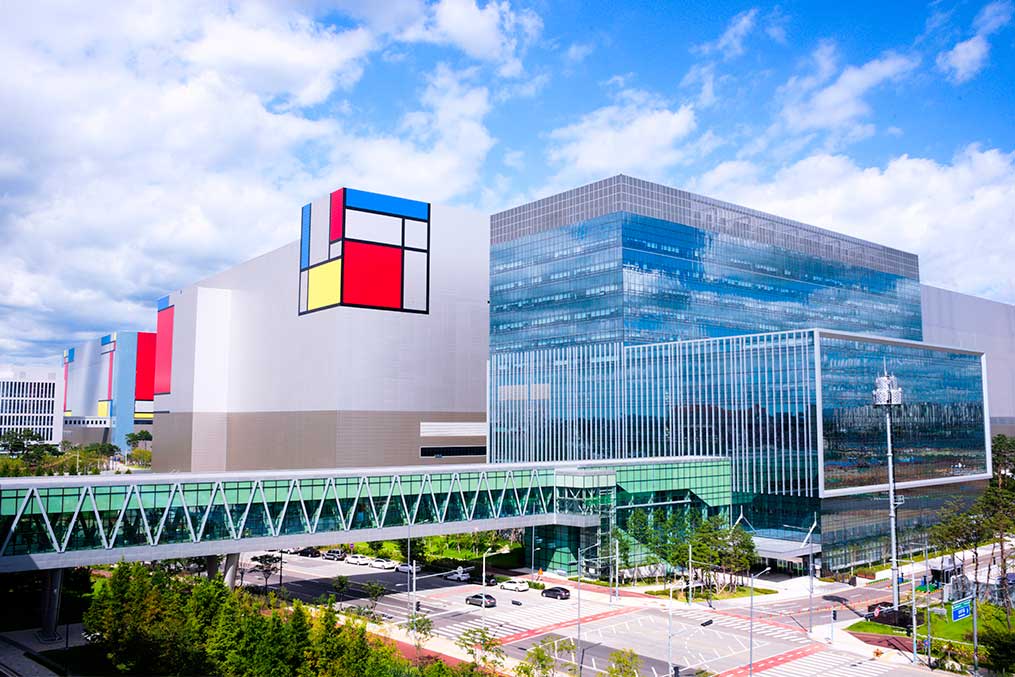 A large building with a vibrant facade stands next to a bridge, symbolizing a new beginning in Korea after leaving San Diego.