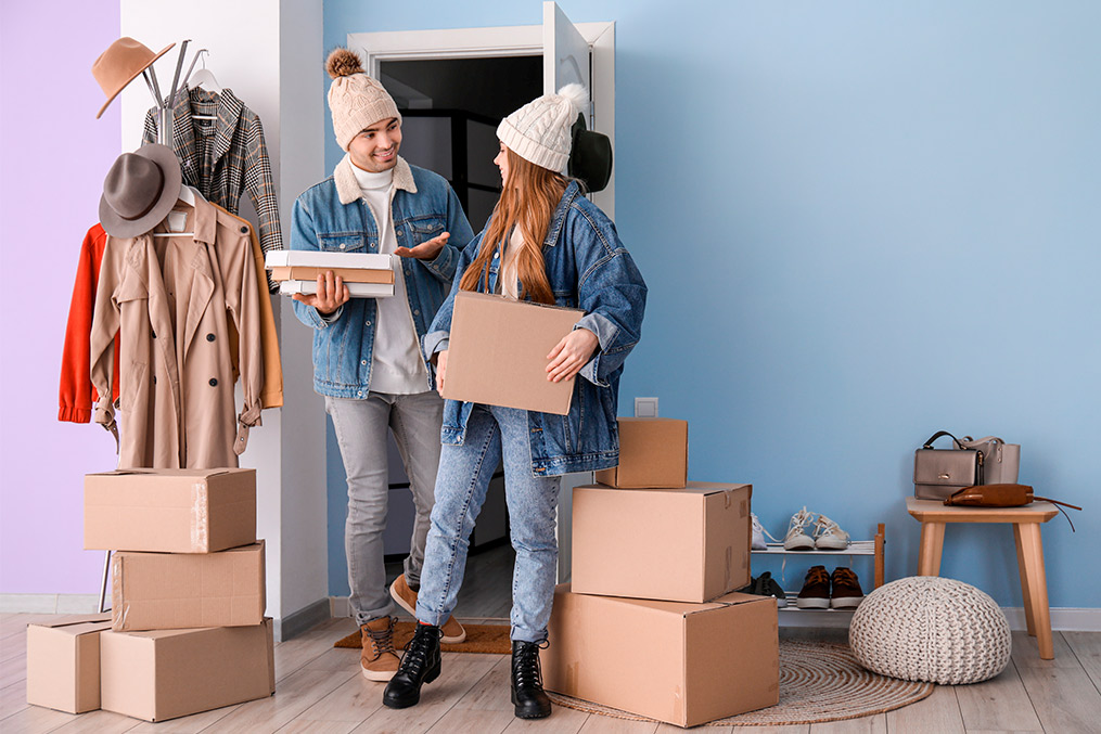 A man and woman are transporting boxes into a room, illustrating the process of winter moving success.