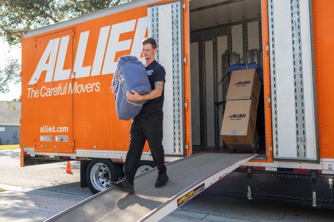 Mover carrying a moving box from a truck. Atlas Allied moving company. 