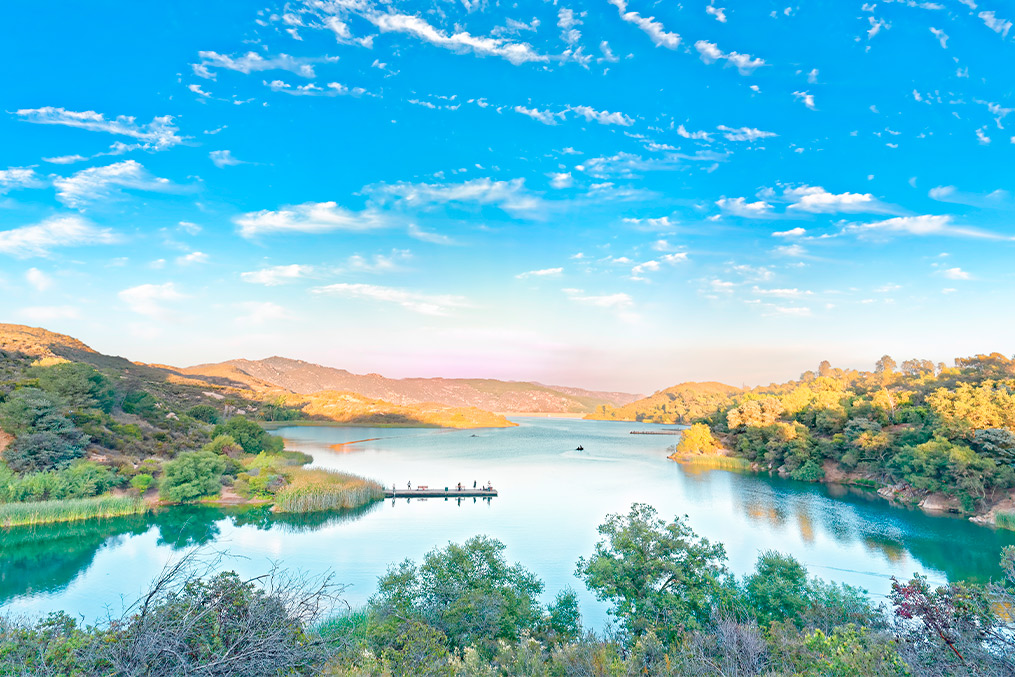 A serene lake nestled among lush hills and trees, illustrating the natural beauty of Escondido, CA.