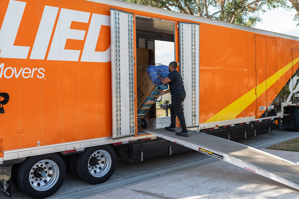 A man packing a truck with a trailer, representing the logistics of relocating to Escondido, CA.