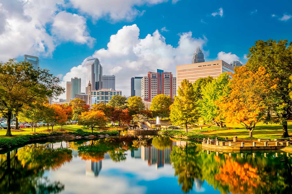 Reflection of a city skyline in park water, illustrating the move from San Diego to Charlotte, NC.