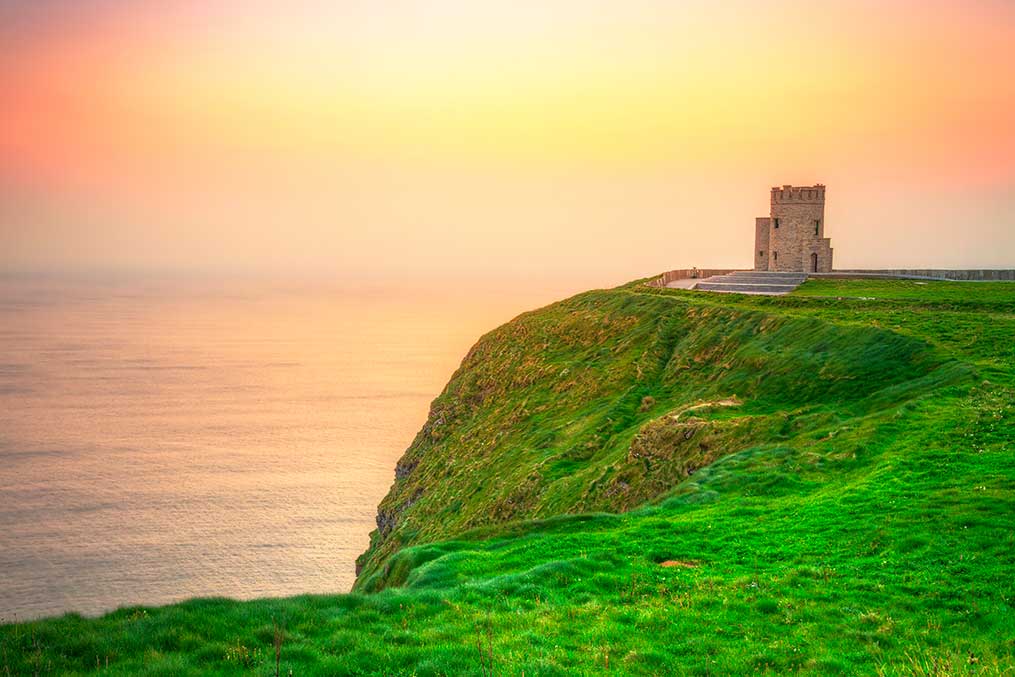 A stunning cliffside castle with ocean views, representing a transition from California to Ireland.