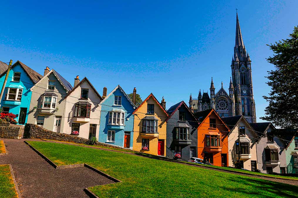 A vibrant hillside of houses in front of a cathedral, representing a transition from California to Ireland.