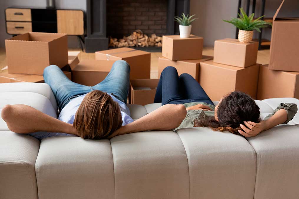 A couple lies on a couch in front of packed boxes, getting ready for their move from California to Ireland.