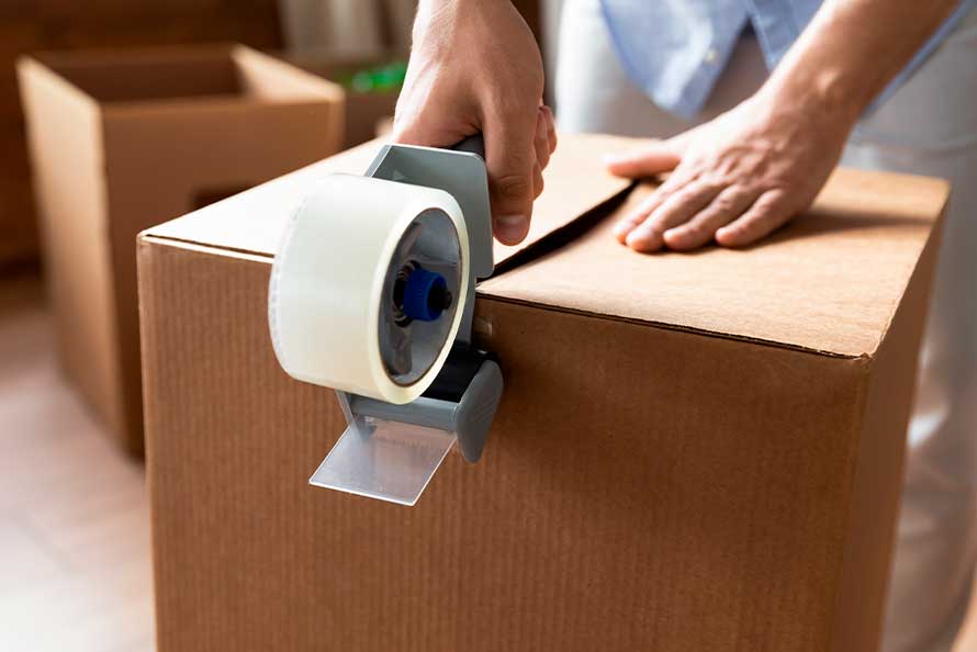 A man secures a box with tape while preparing for his move from San Diego to Raleigh.