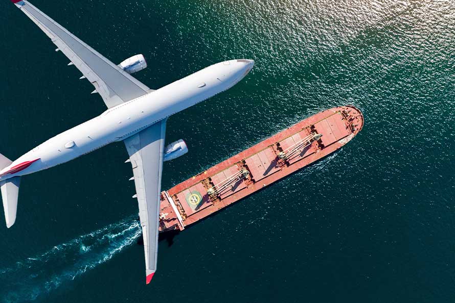 An airplane soars above a cargo ship in the ocean, representing a move from San Diego to London.