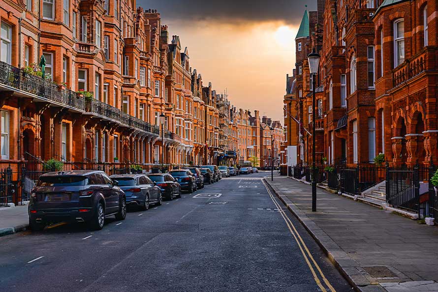 Sunset casts a warm glow on a street lined with red brick buildings, marking a transition from San Diego to London.