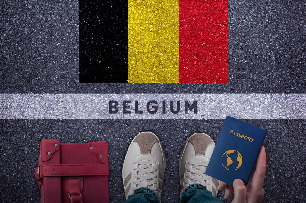 Travel to Belgium. Traveler perspective with bag, passport and Belgium flag on asphalt road